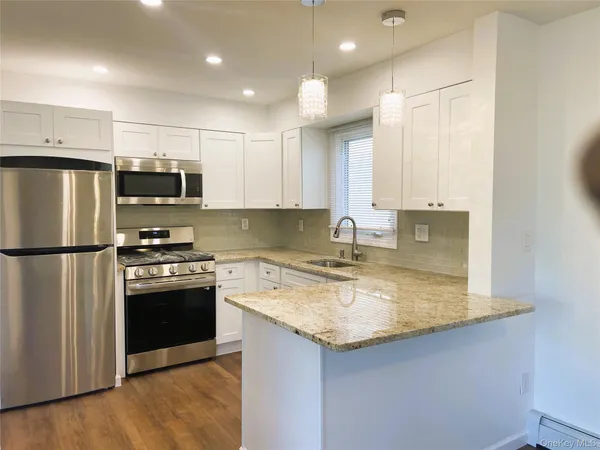 a kitchen with stainless steel appliances granite countertop a refrigerator a stove a sink and a microwave