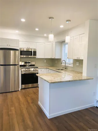 a kitchen with stainless steel appliances granite countertop a refrigerator a stove a sink dishwasher and a microwave with wooden floor