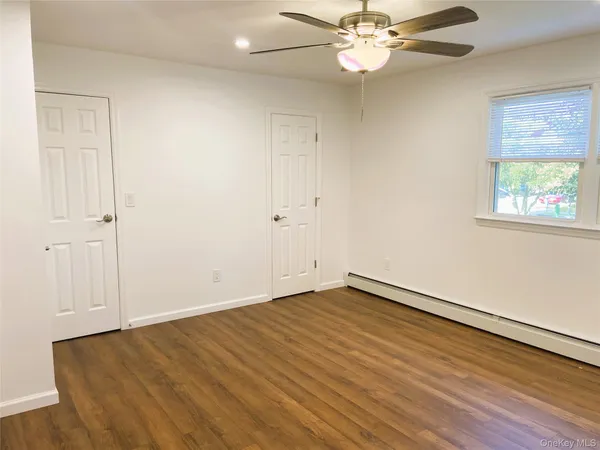 an empty room with wooden floor fan and windows