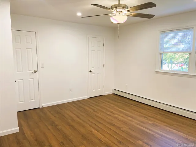 an empty room with wooden floor fan and windows
