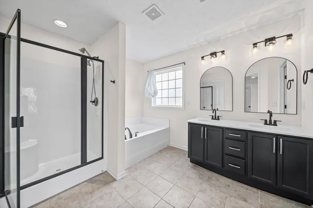 a spacious bathroom with a double vanity sink mirror and bathtub