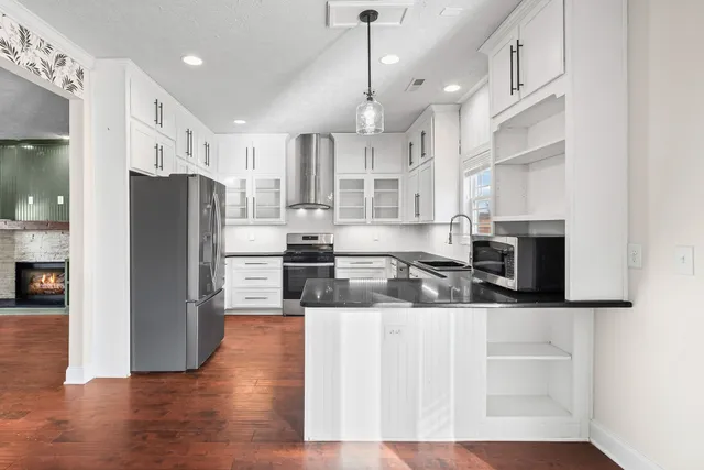 a kitchen with stainless steel appliances granite countertop a refrigerator a sink a stove and a wooden floors