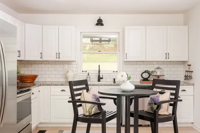 a kitchen with stainless steel appliances kitchen island granite countertop a dining table and chairs