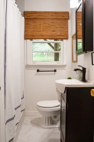 a bathroom with a sink a toilet and a window