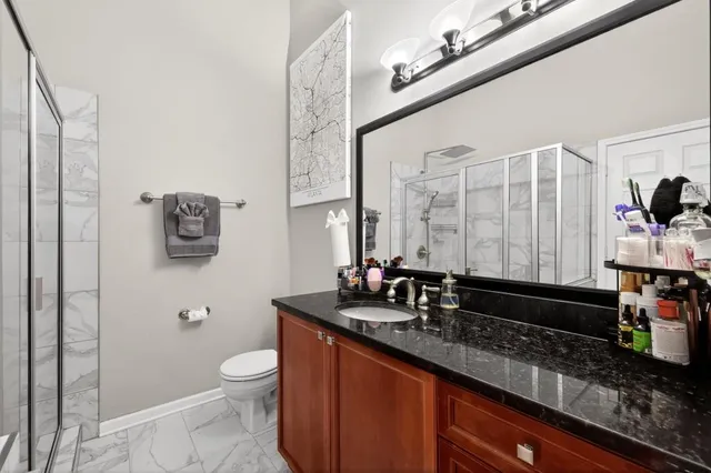 a bathroom with a granite countertop sink a toilet a mirror and shower