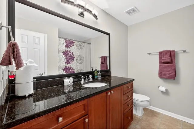 a bathroom with a granite countertop sink a toilet and a mirror