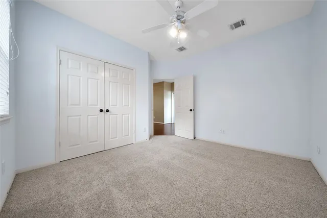 an empty room with a window and a ceiling fan