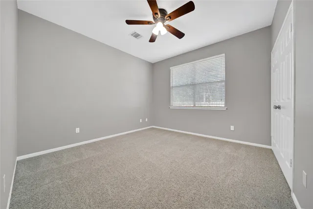 an empty room with a window and a ceiling fan