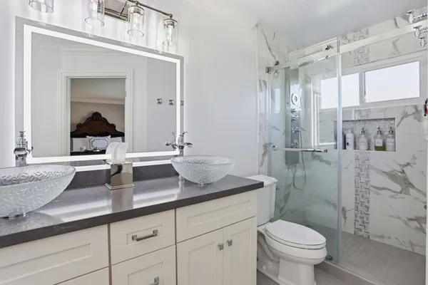 a bathroom with a granite countertop sink a toilet a mirror and shower