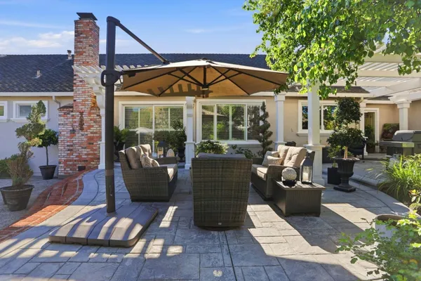 a view of a patio with couches table and chairs under an umbrella