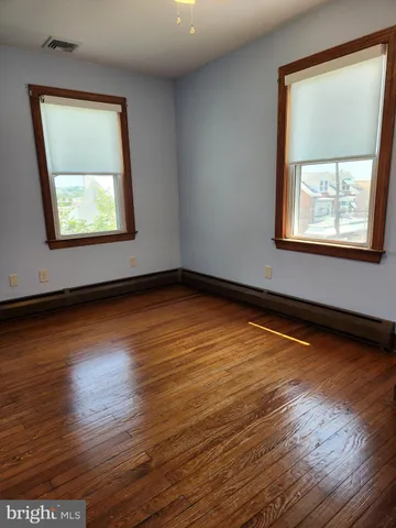 an empty room with wooden floor and window