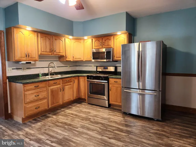 an empty room with wooden floor and a ceiling fan