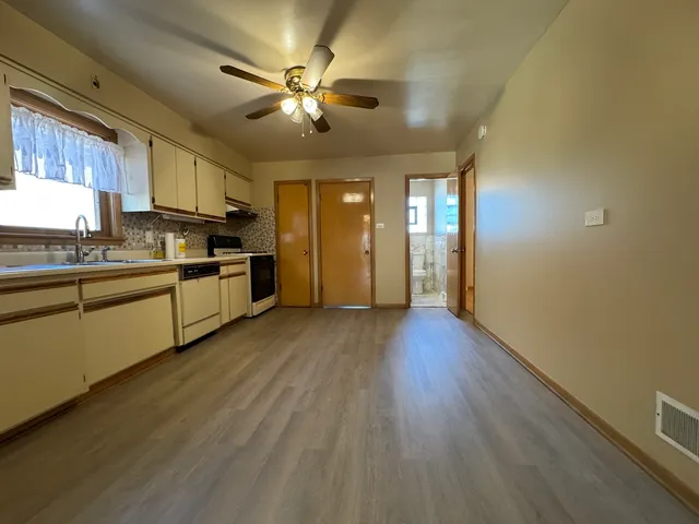 a view of a kitchen with a sink a ceiling fan and wooden floor