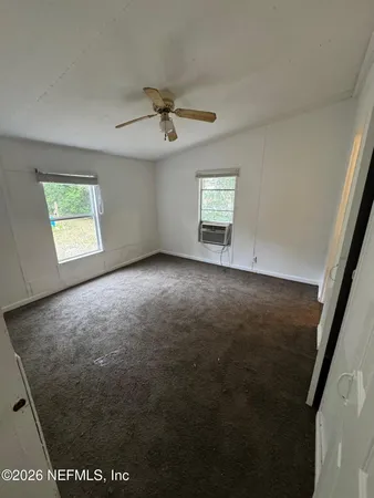 an empty room with windows and fan