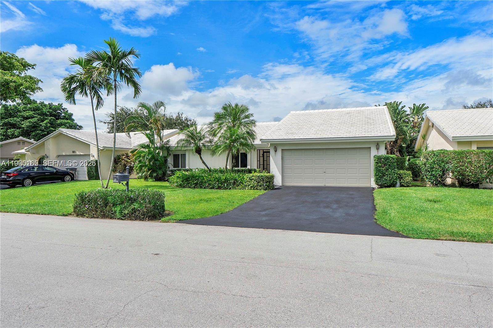 front view of house with a yard and palm trees