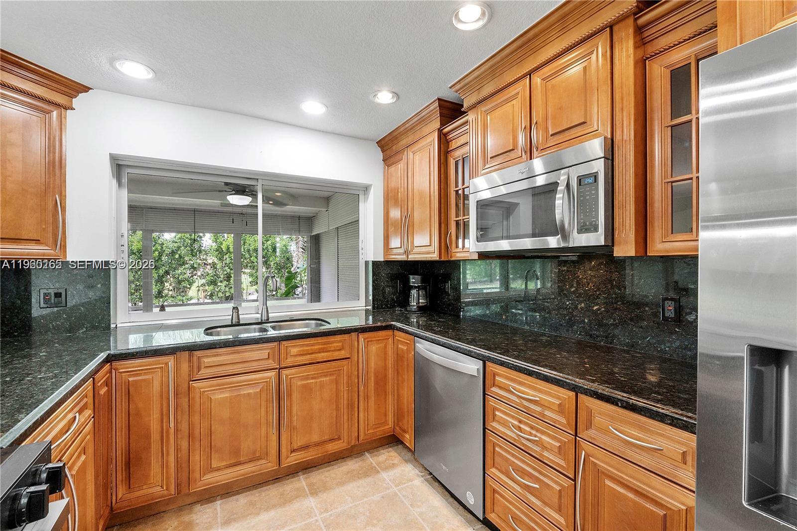 5667 North Cameo Drive Boca Raton, FL 33433 - Photo 22 of 32 a kitchen with stainless steel appliances granite countertop a sink and cabinets