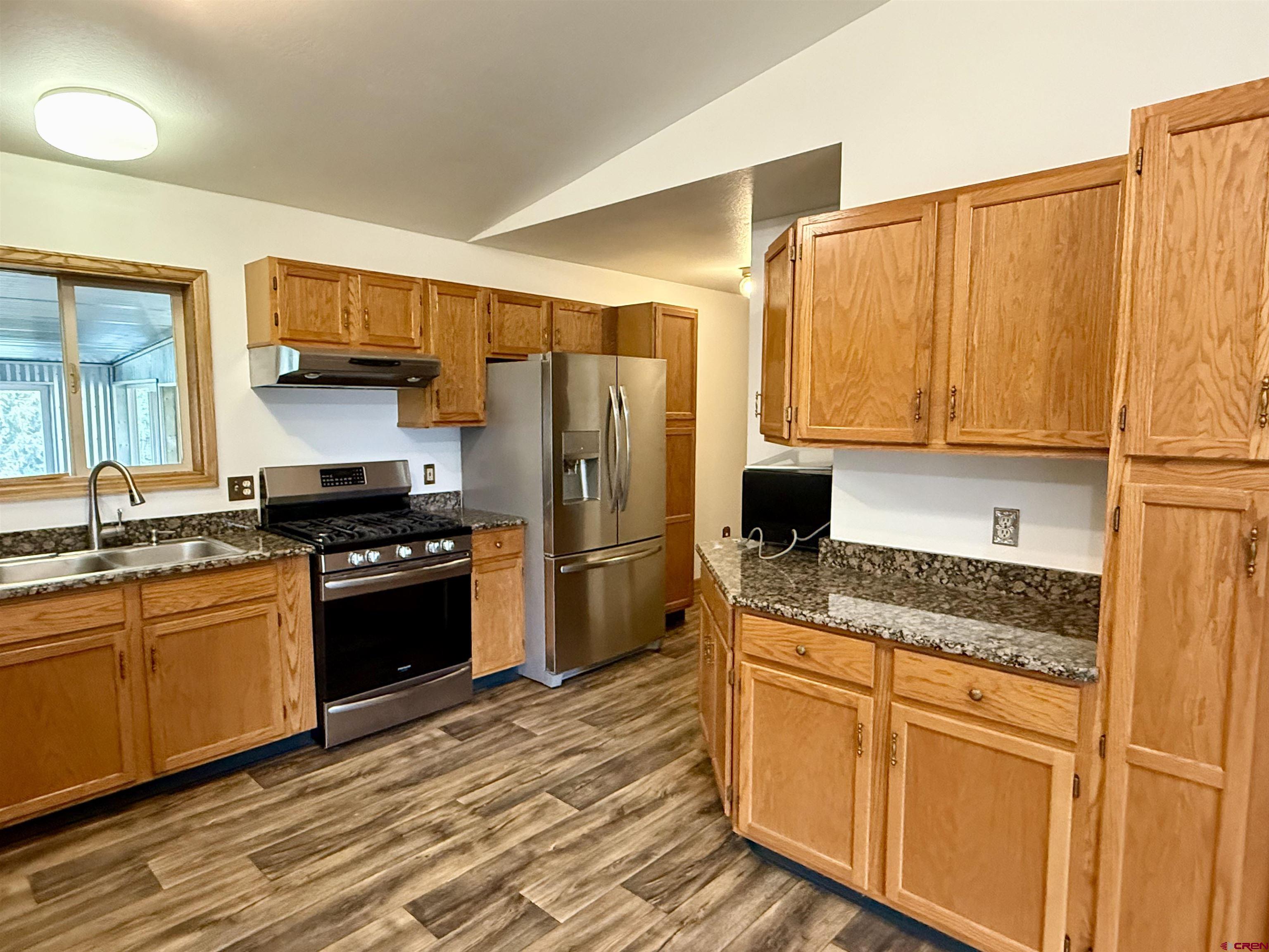 14894 Deer Run Road Delta, CO 81416 - Photo 10 of 40 a kitchen with granite countertop a refrigerator stove top oven and sink