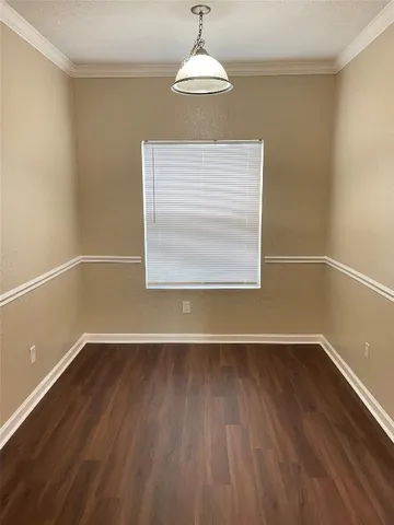 an empty room with wooden floor a exposed radiator and a window