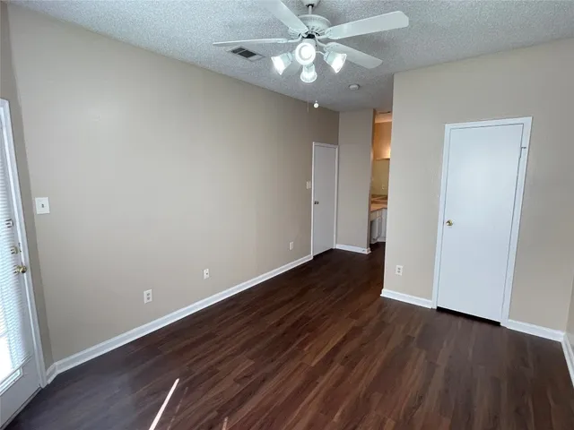 an empty room with wooden floor and ceiling fan