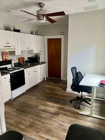 a kitchen with stainless steel appliances kitchen island granite countertop a sink cabinets and wooden floor