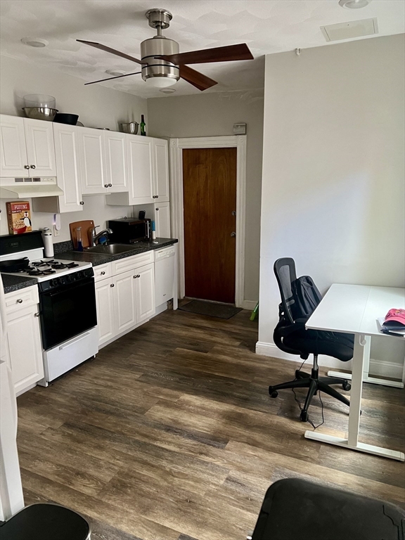 a kitchen with stainless steel appliances kitchen island granite countertop a sink cabinets and wooden floor