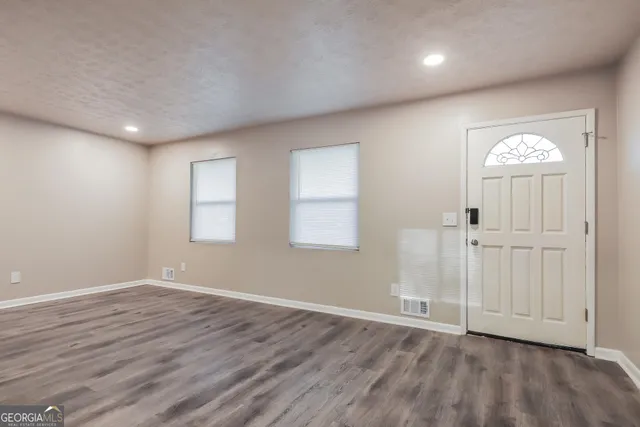 an empty room with wooden floor a ceiling fan and windows