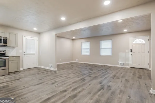 a view of an empty room with window and wooden floor