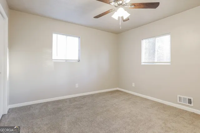 an empty room with a window and a chandelier fan