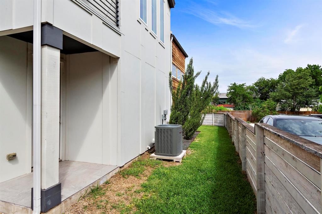911 Stobaugh Street, Unit 2 Austin, TX 78757 - Photo 26 of 26 Side yard featuring a partial wood fence, a patch of green lawn, and an exterior AC unit