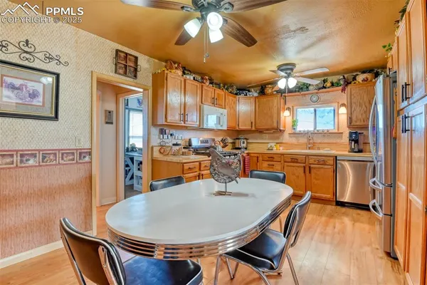 a dining room with stainless steel appliances kitchen island granite countertop a stove a sink dishwasher and a refrigerator with wooden floor