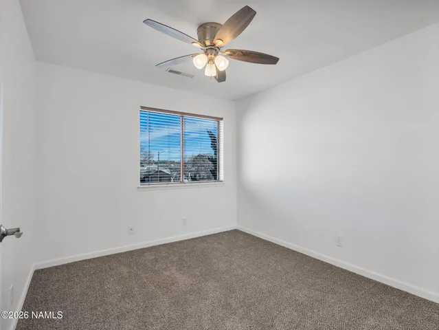 an empty room with a window and a ceiling fan