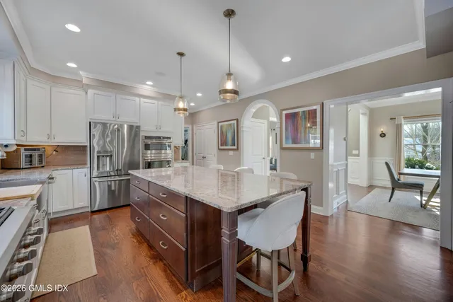 a kitchen with stainless steel appliances granite countertop a kitchen island hardwood floor and a sink