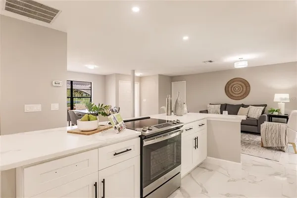 a kitchen with a stove cabinets and living room
