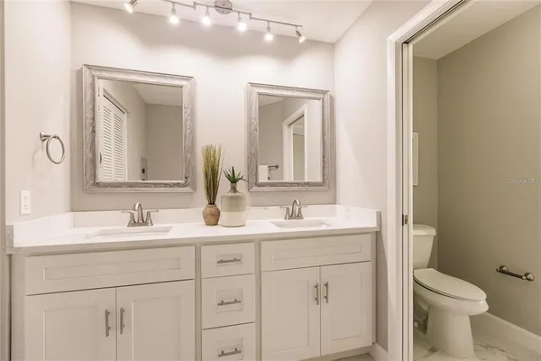 a bathroom with a double vanity sink mirror and toilet