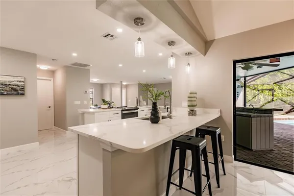 a kitchen with stainless steel appliances kitchen island granite countertop a table chairs sink and cabinets