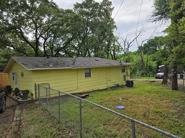 a view of a backyard with large trees and wooden fence