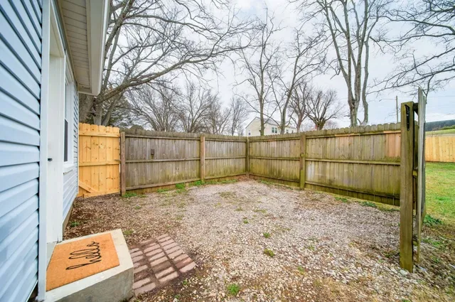 a view of backyard with wooden fence and large trees