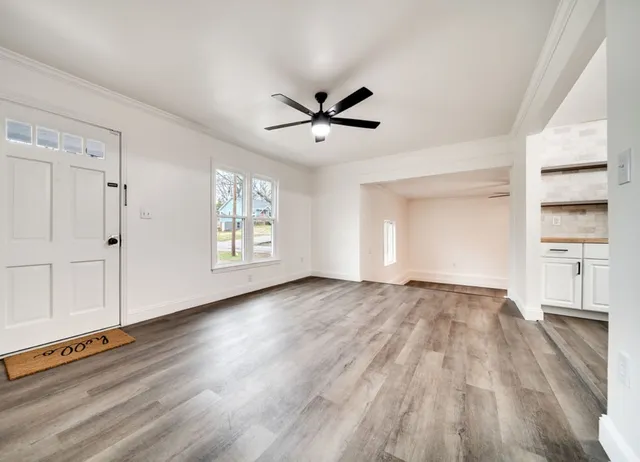 an empty room with wooden floor cabinet and windows