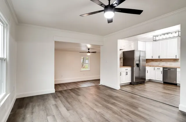 a view of empty room with wooden floor and fan