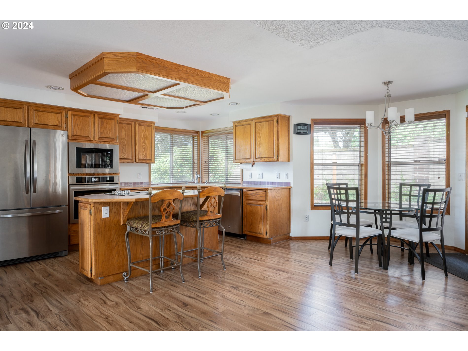 1908 Northwest 140th Circle Vancouver, WA 98685 - Photo 13 of 46 a kitchen with stainless steel appliances kitchen island granite countertop a refrigerator a stove a sink a dining table and chairs with wooden floor