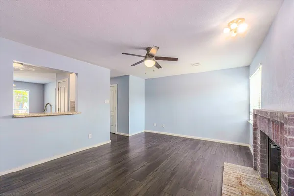 an empty room with wooden floor a fireplace and a window