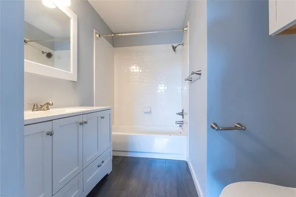 a bathroom with a tub shower sink vanity and a toilet