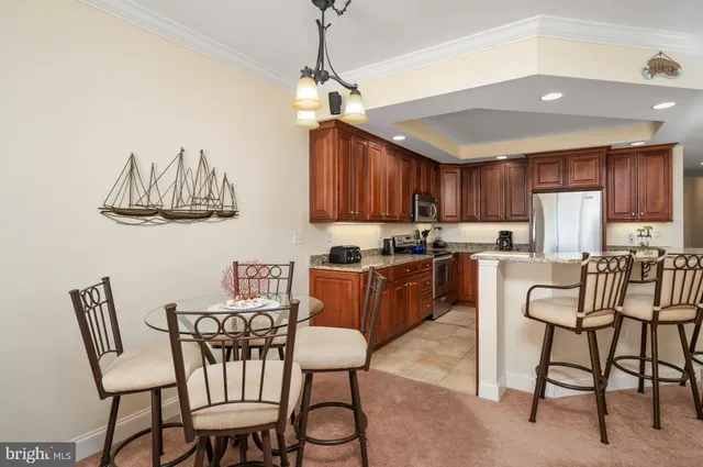 a kitchen with stainless steel appliances granite countertop a dining table chairs and a refrigerator