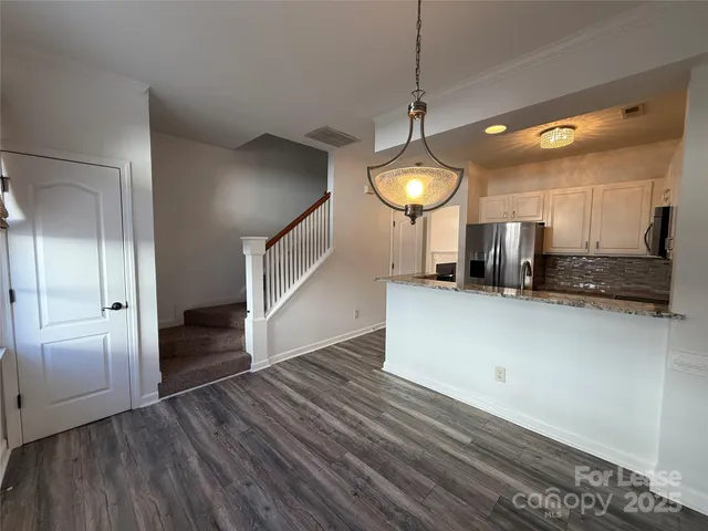 an empty room with wooden floor wooden cabinet and a view of kitchen