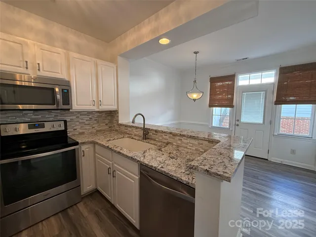 a kitchen with granite countertop a sink cabinets and stainless steel appliances