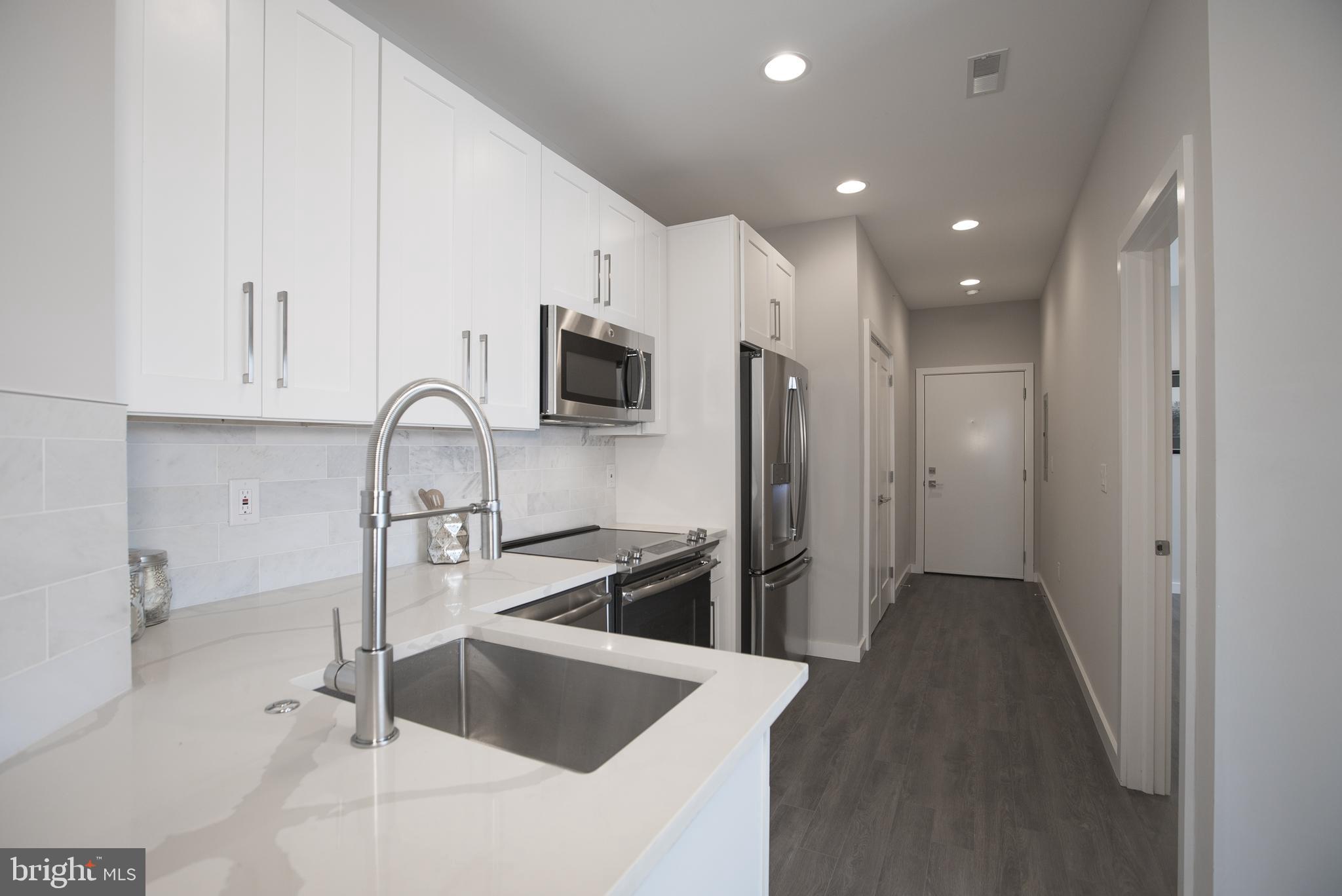 1508 Ridge Avenue, Unit 501 Philadelphia, PA 19130 - Photo 7 of 19 a kitchen with stainless steel appliances granite countertop a refrigerator a sink a stove and white cabinets