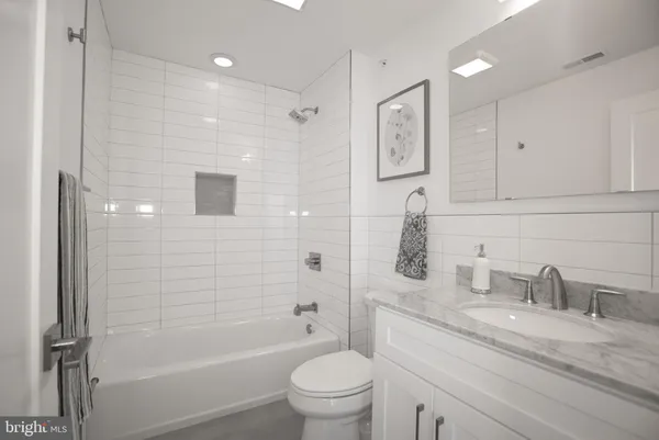 a bathroom with a granite countertop sink a toilet and shower