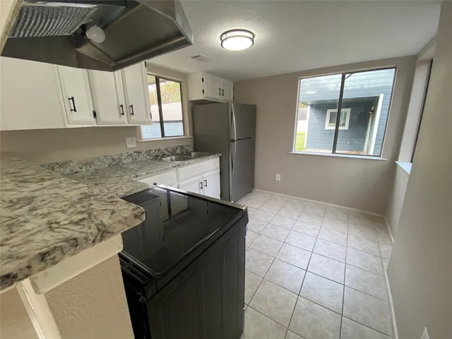 a kitchen with granite countertop a stove a sink and a refrigerator