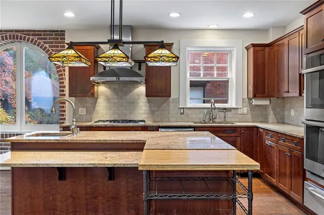 a kitchen with kitchen island granite countertop wooden cabinets and a stove