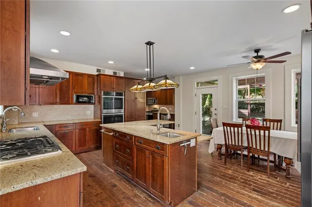 a kitchen with stainless steel appliances granite countertop wooden cabinets a stove top oven a sink and dishwasher